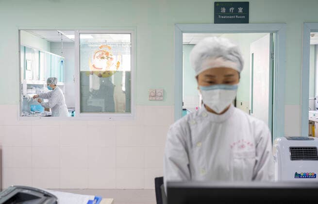 (200404) -- WUHAN, April 4, 2020 -- A medical member (L) works while another pays a silent tribute to martyrs who died in the fight against the novel coronavirus disease (COVID-19) outbreak and compatriots who died of the disease in Wuhan, central China s Hubei Province, April 4, 2020. ) CHINA-COVID-19 VICTIMS-NATIONAL MOURNING (CN) CaixYang 