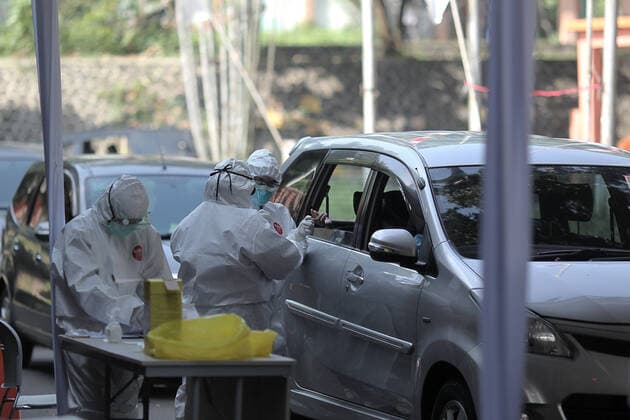 COVID-19 Rapid Test in Bogor, Indonesia - April 4, 2020. A Health workers wearing a protective suit check citizens during the COVID-19 rapid test using the drive thru system in Bogor, West Java, Indonesia, April 4, 2020. The COVID-19 Rapid Test is conducted to speed up the examination process and narrow the spread of Coronavirus (Covid-19) transmission in Bogor, West Java. (Photo by Aditya Saputra INA Photo Agency imago images) 
