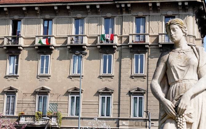 Milan, Coronavirus, People walking with their dog and Italian flags hanging on the balconies of Piazza Giulio Cesare with Le Quatro Stagioni fountain (Duilio Piaggesi Fotogramma, Milan - 2020-04-04) p.s. la foto e utilizzabile nel rispetto del contesto in cui e stata scattata, e senza intento diffamatorio del decoro delle persone rappresentate  Copyright: xDuilioxPiaggesix xFOTOGRAMMAx
