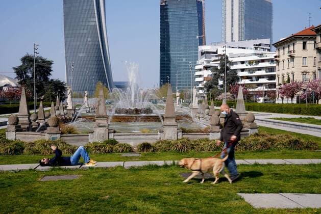 Milan, Coronavirus, People walking with their dog and Italian flags hanging on the balconies of Piazza Giulio Cesare with Le Quatro Stagioni fountain (Duilio Piaggesi Fotogramma, Milan - 2020-04-04) p.s. la foto e utilizzabile nel rispetto del contesto in cui e stata scattata, e senza intento diffamatorio del decoro delle persone rappresentate  Copyright: xDuilioxPiaggesix xFOTOGRAMMAx