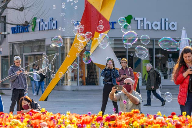 DEU, Germany, Baden Württemberg, Stuttgart, 04 04 2020 Contact ban effective Despite beautiful spring weather, most people stick to the contact ban and travel alone or in pairs In front of the Kunstmuseum am Schlossplatz, a street artist creates soap bubbles