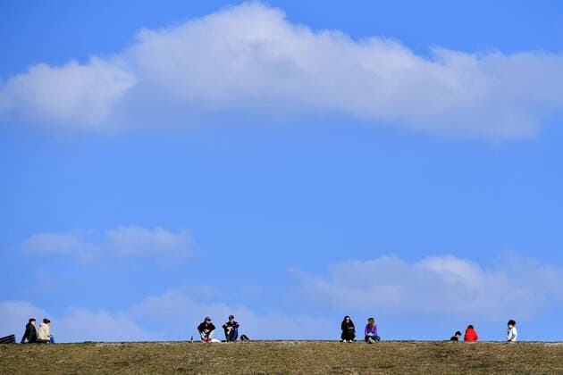 Public life in times of the corona pandemic on 04 04 2020 in Riemer Park in Munich Families, people, persons sitting in the grass on a hill in front of a blue sky The spring weather drives the population to fresh air, always with the necessary distance because of an infection with the corona virus.