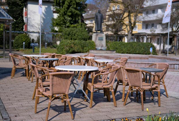 05 04 2020, Shops and restaurants close due to corona virus pandemic in Bad Wörishofen, Yawning empty tables stand without guests at the monument square in the pedestrian zone, the daffodils bloom beautifully in the flowerbed 05 04 2020, Closed restaurants due to corona virus 05 04 2020, Closed restaurants due to corona virus