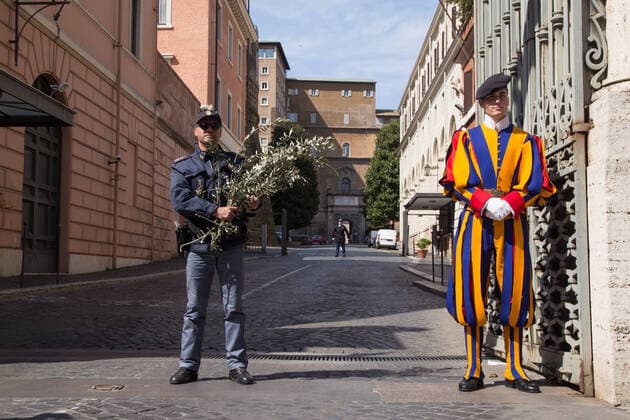 Palm Sunday in St. Peter s Square during CoVID-19 View of the Porta Sant Anna of the Vatican City with carabinieri and a Swiss guard Palm Sunday in St. Peter s Square in Rome in this lockdown period due to the Covid-19 pandemic Roma Italy Copyright: MatteoxNardone