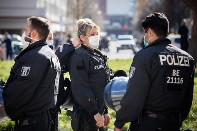Conspiracy theorists protest gg Corona restrictions A policewoman helps her colleague on the edge of a demonstration of conspiracy theorists during the containment ordinance with exit restriction, demonstration ban and contact ban to contain the COVID 19 pandemic Coronavirus SARS CoV 2 in Berlin to put on a breathing mask Â Berlin Berlin Germany