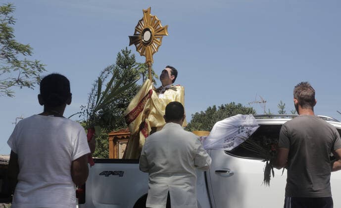 Coronavirus in Brasilien, motorisierte Prozession zum Beginn der Karwoche in Campo Mourao CAMPO MOURÃO, PR - 05.04.2020: COVID 19 ESPANTA FIES NO DOMINGO DE RAMOS - Catholics in Campo Mourão, in the Midwest Region of Paraná, celebrated Palm Sunday? beginning of Holy Week? from the gate into the residences. The faithful placed a green branch on the gates of the houses waiting for the passage of the Most Holy. Due to the recommendation of social isolation due to the Covid-19 pandemic, a disease caused by the coronavirus, a priest held a small procession blessing the homes and people of neighborhoods close to the city center. In the photo, faithful celebrate Palm Sunday from the gate of their homes. x1901690x  DirceuxPortugal