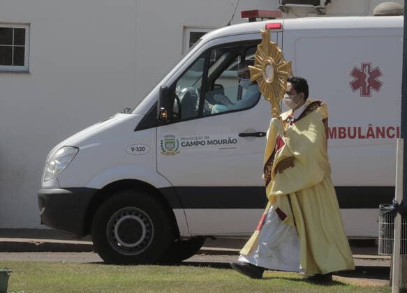 Coronavirus in Brasilien, motorisierte Prozession zum Beginn der Karwoche in Campo Mourao CAMPO MOURÃO, PR - 05.04.2020: COVID 19 ESPANTA FIES NO DOMINGO DE RAMOS - Catholics in Campo Mourão, in the Midwest Region of Paraná, celebrated Palm Sunday? beginning of Holy Week? from the gate into the residences. The faithful placed a green branch on the gates of the houses waiting for the passage of the Most Holy. Due to the recommendation of social isolation due to the Covid-19 pandemic, a disease caused by the coronavirus, a priest held a small procession blessing the homes and people of neighborhoods close to the city center. In the photo, a priest visits the sick at Santa Casa de Campo Mourão. x1901709x  DirceuxPortugal