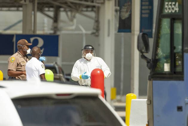 April 5, 2020, Miami, FL, USA: Miami-Dade Police, alongside security personnel from the port, wait for Coral Princess cruise passengers to board buses at PortMiami as the coronavirus pandemic continues on Sunday, March 5, 2020 in Miami. Miami USA - ZUMAm67_ 20200405_zaf_m67_029 Copyright: xDavidxSantiagox