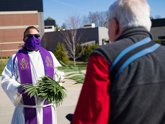 Coronavirus in den USA, Drive-Through Gottesdienst zum Auftakt der Karwoche in Des Moines, Iowa April 5, 2020, Des Moines, Iowa, U.S: Rev. RUSSELL LACKEY, left, follows Social Distancing guidelines while he hands out palms during a drive through Palm Sunday service sponsored by Luther Memorial Church on the campus of Grand View University in Des Moines. About 150 people attended the service. They remained in their cars while the ministers read a short passage from the Bible, handed out palms and blessed them. On Sunday, 05 April, Iowa reported 868 confirmed cases of the Novel Coronavirus (SARS-CoV-2) and COVID-19. There have been 22 deaths attributed to COVID-19 in Iowa. Restaurants, bars, movie theaters, places that draw crowds are closed until 30 April. The Governor has not ordered shelter in place but several Mayors, including the Mayor of Des Moines, have asked residents to stay in their homes for all but essential needs - ZUMAk94_ 20200405_zaf_k94_001 Copyright: xJackxKurtzx