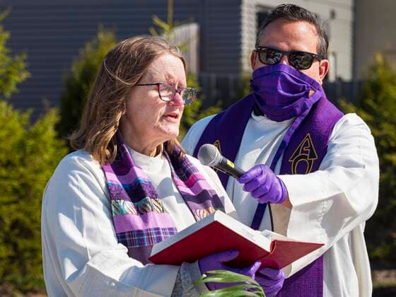 Coronavirus in den USA, Drive-Through Gottesdienst zum Auftakt der Karwoche in Des Moines, Iowa April 5, 2020, Des Moines, Iowa, U.S: Rev. RUSSELL LACKEY, right, holds the microphone for Rev. BONNIE PARKER, who read from the Bible, during a drive through Palm Sunday service sponsored by Luther Memorial Church on the campus of Grand View University in Des Moines. About 150 people attended the service. They remained in their cars while the ministers read a short passage from the Bible, handed out palms and blessed them. On Sunday, 05 April, Iowa reported 868 confirmed cases of the Novel Coronavirus (SARS-CoV-2) and COVID-19. There have been 22 deaths attributed to COVID-19 in Iowa. Restaurants, bars, movie theaters, places that draw crowds are closed until 30 April. The Governor has not ordered shelter in place but several Mayors, including the Mayor of Des Moines, have asked residents to stay in their homes for all but essential - ZUMAk94_ 20200405_zaf_k94_014 Copyright: xJackxKurtzx