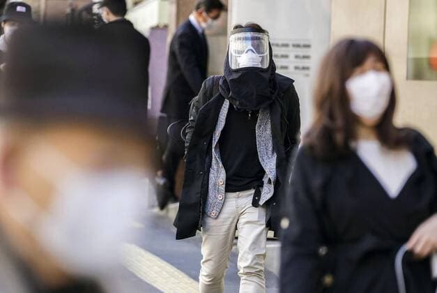 Coronavirus in Japan, Eindrücke aus Tokio New coronavirus A man (C) walks with his face fully covered with a protective shield in front of JR Shinjuku Station in Tokyo on April 6, 2020, amid the spread of the coronavirus. 