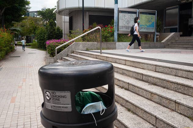 02 04 2020, Singapore, Republic of Singapore, Asia A discarded mouthguard hangs in a garbage can in front of a subway station in the city centre