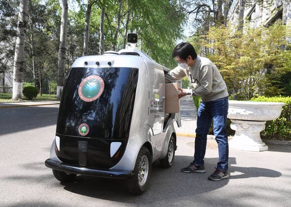 (200406) -- BEIJING, April 6, 2020 -- A member of staff takes goods from a 5G unmanned delivery car at the Beijing Institute of Technology in Beijing, capital of China, April 6, 2020. A 5G unmanned delivery car was put into use at the Beijing Institute of Technology, which can measure the temperature of people entering the campus, recognise facial information, and also can conduct no-touch delivery. ) CHINA-BEIJING-CAMPUS-UNMANNED DELIVERY CAR (CN) RenxChao 