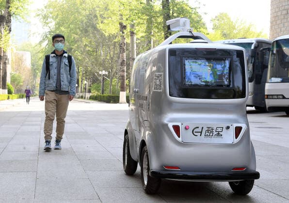 (200406) -- BEIJING, April 6, 2020 -- A 5G unmanned delivery car delivers goods while measuring the temperature of people walking by at the Beijing Institute of Technology in Beijing, capital of China, April 6, 2020. A 5G unmanned delivery car was put into use at the Beijing Institute of Technology, which can measure the temperature of people entering the campus, recognise facial information, and also can conduct no-touch delivery. ) CHINA-BEIJING-CAMPUS-UNMANNED DELIVERY CAR (CN) RenxChao 