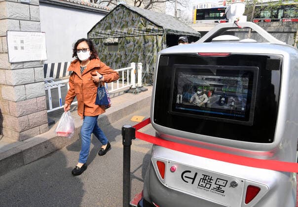 (200406) -- BEIJING, April 6, 2020 -- A 5G unmanned delivery car measures the temperature of a woman walking into the Beijing Institute of Technology in Beijing, capital of China, April 6, 2020. A 5G unmanned delivery car was put into use at the Beijing Institute of Technology, which can measure the temperature of people entering the campus, recognise facial information, and also can conduct no-touch delivery. ) CHINA-BEIJING-CAMPUS-UNMANNED DELIVERY CAR (CN) RenxChao 