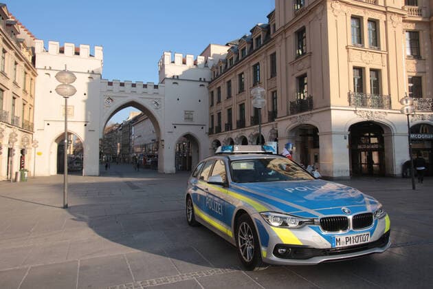 Patrol cars of the Bavarian State Police are parked in front of the Karlstor in the city centre of Munich, Bavaria, Germany, during a check on the occasion of the corona crisis on the compliance with the contact prohibitions and minimum distances at the Karlsplatz Stachus, which is otherwise heavily frequented by passers-by