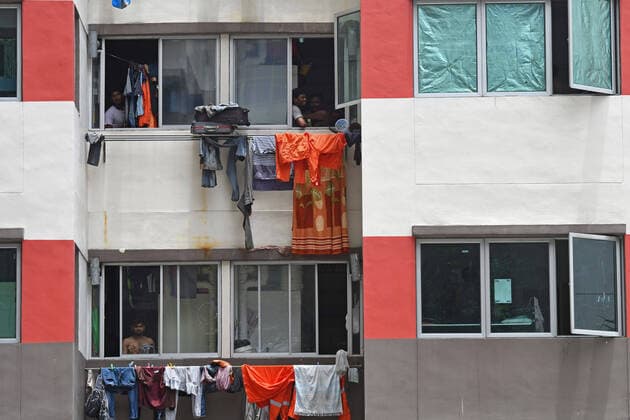 (200406) --SINGAPORE, April 6, 2020 -- A few workers look out the windows at Westlite Toh Guan dormitory in Singapore on April 6, 2020. Singapore s Ministry of Health and Ministry of Manpower said in a joint statement Sunday that transmissions within Singapore s foreign worker dormitories had continued to rise, and the city state was seeing more confirmed cases and ill workers. (Photo by Xinhua) SINGAPORE-COVID-19-DORMITORY ThenxChihxWey 