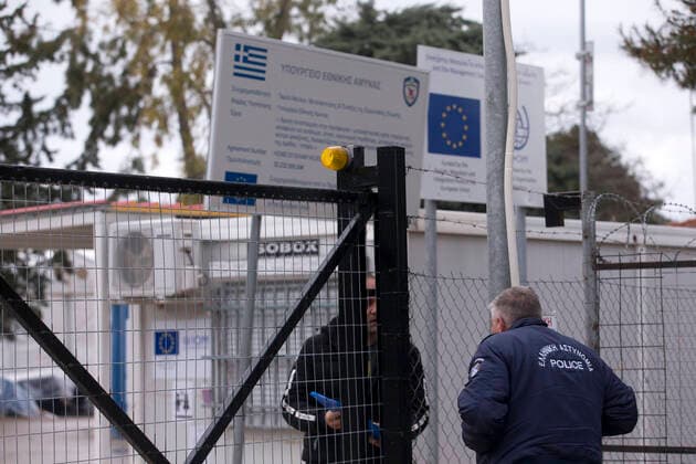 (200406) -- MALAKASA, April 6, 2020 -- A police officer speaks with an employee at the gate of the Malakasa camp near Athens, Greece, April 6, 2020. An Afghan migrant in Malakasa was confirmed to be infected with COVID-19 on Sunday, and the camp has been locked down since then. ) GREECE-MALAKASA-MIGRANTS-CAMP-COVID-19 MariosxLolos 