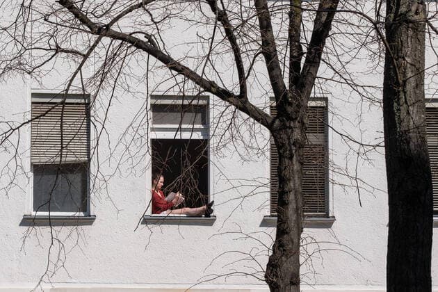 Contact ban Woman sitting in her window in Berlin Prenzlauer Berg and reading a book in warm spring weather Coronakrise Ausgangsbeschramkungen