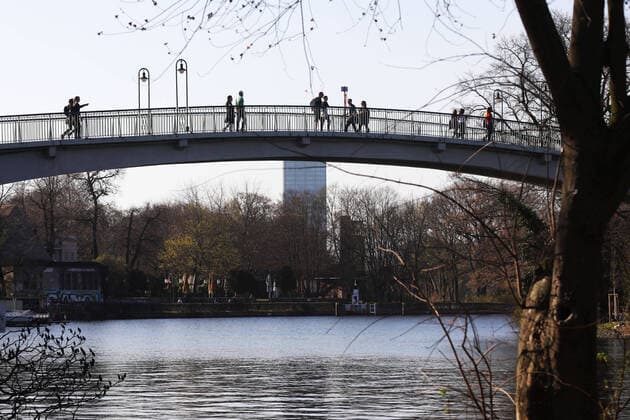 06 04 2020, Berlin Germany In Treptower Park, people enjoy the beautiful weather, they walk over the bridge to the Isle of Youth All observe the distance regulation during the Corona crisis
