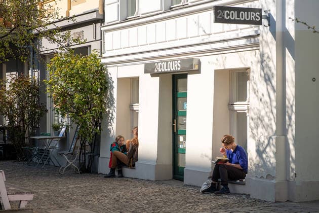 People enjoy the warm and sunny spring weather with enough distance between each other on the window sills of closed shops and cafés Prenzlauer Berg on Oderberger Strasse Coronakrise Spring weather with the virus