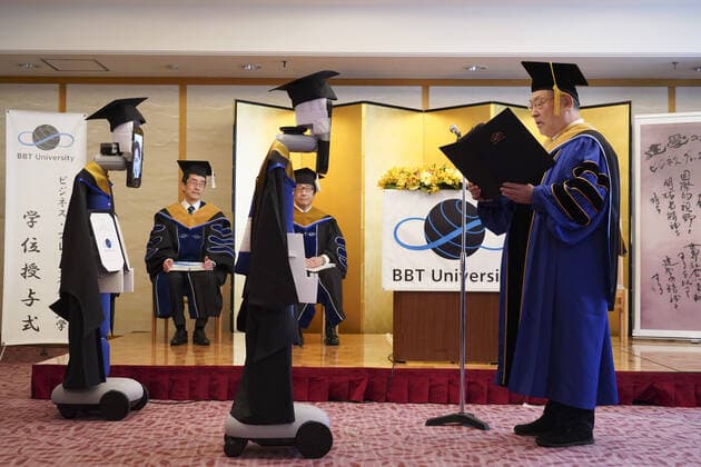 A Japanese University has held the world s first online graduation ceremony using robots due to the coronavirus pandemic. Students at Business Breakthrough University in Tokyo didn t get a traditional ceremony, but had the next best thing using newme telepresensence robots and a tablet hosting a Zoom call. Graduates had the experience of walking across the stage and accepting their diplomas at the Hotel Grand Palace in Tokyo, virtually on March 28, all while self-isolating at home. The robots were dressed in a cap and gown and fitted with tablets on their heads, allowing students to show their face using Zoom. When the moderator called the name, a newme wearing a graduation gown and hat from BBT University appeared on the tablet with the face of the graduate who operated it, and the diploma was handed over by President Omae Kenich Copyright: xx 40432768 EDITORIAL USE ONLY. NOT FOR USE BY NEWSPAPERS BASED IN THE UK.