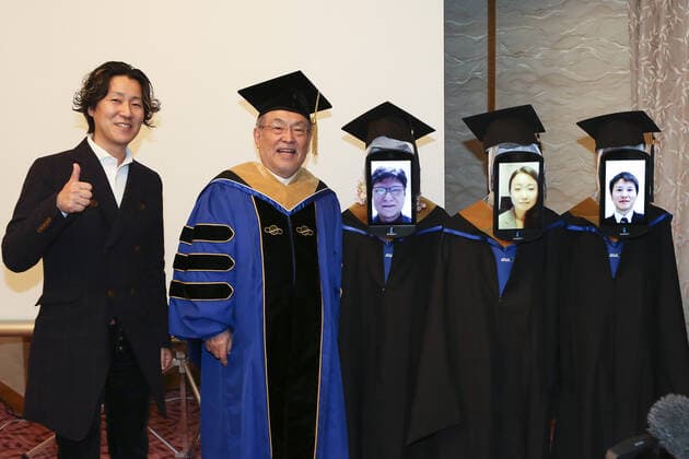 A Japanese University has held the world s first online graduation ceremony using robots due to the coronavirus pandemic. Students at Business Breakthrough University in Tokyo didn t get a traditional ceremony, but had the next best thing using newme telepresensence robots and a tablet hosting a Zoom call. Graduates had the experience of walking across the stage and accepting their diplomas at the Hotel Grand Palace in Tokyo, virtually on March 28, all while self-isolating at home. The robots were dressed in a cap and gown and fitted with tablets on their heads, allowing students to show their face using Zoom. When the moderator called the name, a newme wearing a graduation gown and hat from BBT University appeared on the tablet with the face of the graduate who operated it, and the diploma was handed over by President Omae Kenich Copyright: xx 40432771 EDITORIAL USE ONLY. NOT FOR USE BY NEWSPAPERS BASED IN THE UK.