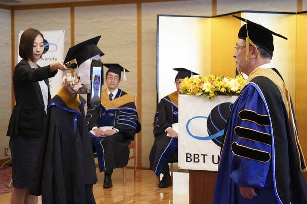 April 7, 2020, Tokyo, Japan: A Japanese University has held the world s first online graduation ceremony using robots due to the coronavirus pandemic...Students at Business Breakthrough University in Tokyo didn t get a traditional ceremony, but had the next best thing using newme telepresensence robots and a tablet hosting a Zoom call...Graduates had the experience of walking across the stage and accepting their diplomas at the Hotel Grand Palace in Tokyo, virtually on March 28, all while self-isolating at home...The robots were dressed in a cap and gown and fitted with tablets on their heads, allowing students to show their face using Zoom...When the moderator called the name, a newme wearing a graduation gown and hat from BBT University appeared on the tablet with the face of the graduate who operated it, and the diploma was hande - ZUMAc218 20200407_zia_c218_017 Copyright: xCOVERxImagesx