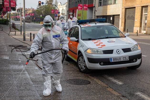 April 7, 2020, Girona, Spain: A civil protection agent dressed in a protective suit sprays disinfectants on the streets..During the Covid-19 crisis, the civil protection agents of Gerona carry out disinfection tasks in residential areas. Girona Spain - ZUMAs197 20200407_zaa_s197_029 Copyright: xDavidxApariciox