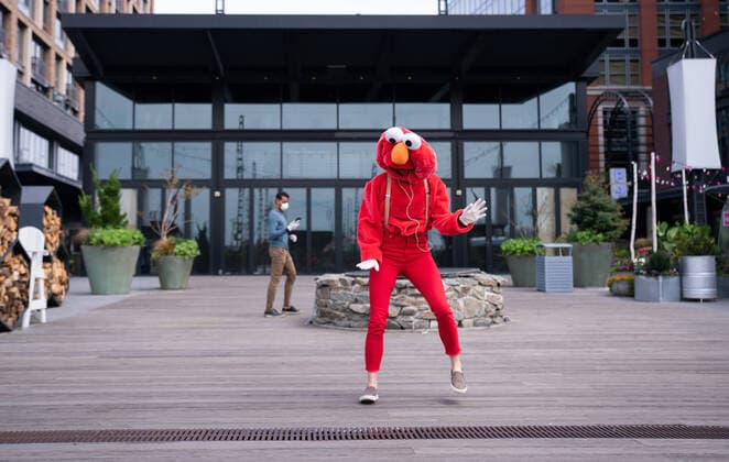 A YouTube performer known as Elmo at the Wharf dances on the Wharf in Washington, D.C. during the Coronavirus pandemic and stay at home order, on Tuesday, April 7, 2020. The performer said she was attempting to bring smiles and joy to the people in the apartment buildings that overlook the area.  WAP20200407314 KEVINxDIETSCH