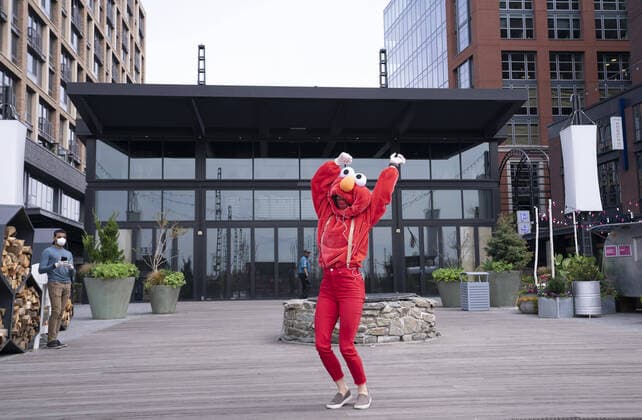 A YouTube performer known as Elmo at the Wharf dances on the Wharf in Washington, D.C. during the Coronavirus pandemic and stay at home order, on Tuesday, April 7, 2020. The performer said she was attempting to bring smiles and joy to the people in the apartment buildings that overlook the area.  WAP20200407315 KEVINxDIETSCH