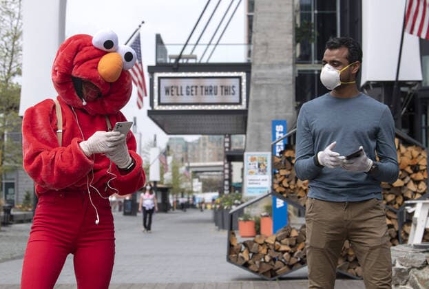 A YouTube performer known as Elmo at the Wharf takes a break with her cameraman after performing on the Wharf in Washington, D.C. during the Coronavirus pandemic and stay at home order, on Tuesday, April 7, 2020. The performer said she was attempting to bring smiles and joy to the people in the apartment buildings that overlook the area.  WAP20200407324 KEVINxDIETSCH