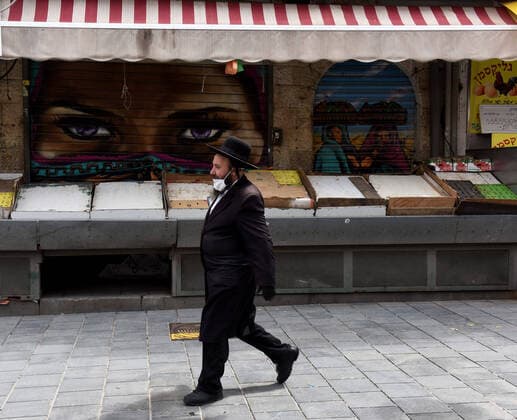 An Ultra-Orthodox Jew wears a mask and gloves, as protection from the coronavirus, while shopping for the Jewish holiday Passover in the Mahane Yehuda Market, on Tuesday, March 7, in Jerusalem. Israeli Prime Minister Benjamin announced severe travel restrictions and a curfew for the Passover holiday, as an effort to halt the spread of the coronavirus.  JER2020040707 DEBBIExHILL