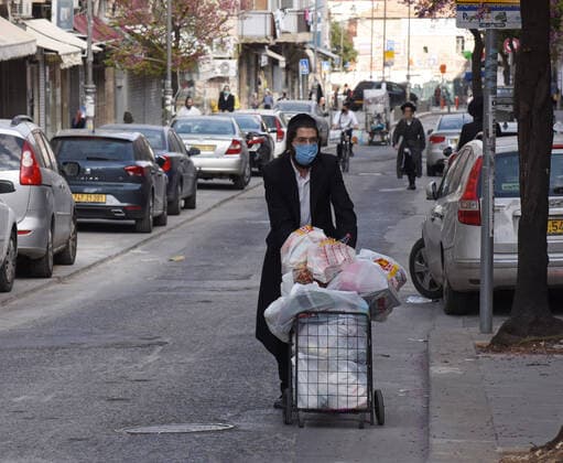 An Ultra-Orthodox Jew wears a mask, as protection from the coronavirus, while shopping for the Jewish holiday Passover, on Tuesday, March 7, in Mea Shearim, Jerusalem. Israeli Prime Minister Benjamin announced severe travel restrictions and a curfew for the Passover holiday, as an effort to halt the spread of the coronavirus.  JER2020040712 DEBBIExHILL