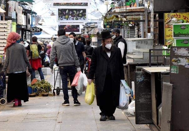 An Ultra-Orthodox Jew wears a mask and gloves, as protection from the coronavirus, while shopping for the Jewish holiday Passover in the Mahane Yehuda Market, on Tuesday, March 7, in Jerusalem. Israeli Prime Minister Benjamin announced severe travel restrictions and a curfew for the Passover holiday, as an effort to halt the spread of the coronavirus.  JER2020040706 DEBBIExHILL