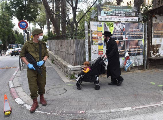 An Israeli soldier wears a mask and gloves, as protection from the coronavirus, while enforcing movement restrictions, before the Jewish holiday Passover, on Tuesday, March 7, in Jerusalem. Israeli Prime Minister Benjamin announced severe travel restrictions and a curfew for the Passover holiday, as an effort to halt the spread of the coronavirus.  JER2020040710 DEBBIExHILL