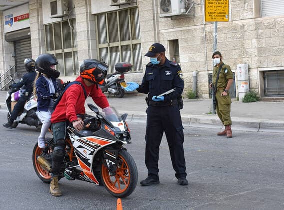 An Israeli police wears a mask and gloves, as protection from the coronavirus, while enforcing movement restrictions, before the Jewish holiday Passover, on Tuesday, March 7, in Jerusalem. Israeli Prime Minister Benjamin announced severe travel restrictions and a curfew for the Passover holiday, as an effort to halt the spread of the coronavirus.  JER2020040711 DEBBIExHILL
