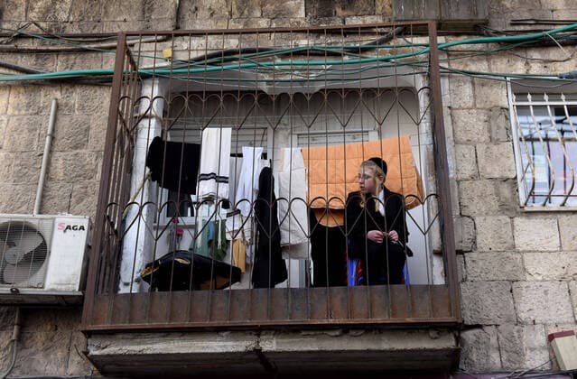 An Ultra-Orthodox Jewish boy sits on a balcony, on Tuesday, March 7, in the Mea Shearim, Jerusalem. Israeli Prime Minister Benjamin announced severe travel restrictions and a curfew for the Passover holiday, as an effort to halt the spread of the coronavirus.  JER2020040716 DEBBIExHILL