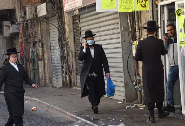 An Ultra-Orthodox Jew wears a mask, as protection from the coronavirus, while shopping for the Jewish holiday Passover, on Tuesday, March 7, in Mea Shearim, Jerusalem. Israeli Prime Minister Benjamin announced severe travel restrictions and a curfew for the Passover holiday, as an effort to halt the spread of the coronavirus.  JER2020040717 DEBBIExHILL