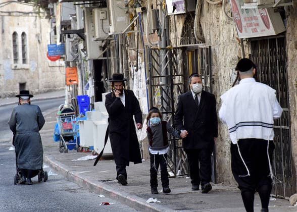 An Ultra-Orthodox Jew and his son wears masks, as protection from the coronavirus, while shopping for the Jewish holiday Passover, on Tuesday, March 7, in Mea Shearim, Jerusalem. Israeli Prime Minister Benjamin announced severe travel restrictions and a curfew for the Passover holiday, as an effort to halt the spread of the coronavirus.  JER2020040718 DEBBIExHILL