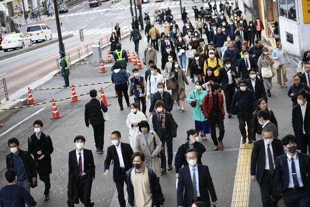 TOKYO, JAPAN - APRIL 7: Commuters wearing masks walk across the street in Shinjuku business district, Tuesday, April 7, 2020, in Tokyo. Japanese Prime Minister Shinzo Abe declared a state of emergency on Tuesday for Tokyo and six other prefectures to ramp up defenses against the spread of the coronavirus. (Photo: Richard Atrero de Guzman AFLO)  (125133468)