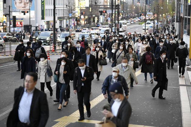 TOKYO, JAPAN - APRIL 7: Commuters wearing masks walk across the street in Shinjuku business district, Tuesday, April 7, 2020, in Tokyo. Japanese Prime Minister Shinzo Abe declared a state of emergency on Tuesday for Tokyo and six other prefectures to ramp up defenses against the spread of the coronavirus. (Photo: Richard Atrero de Guzman AFLO)  (125133487)