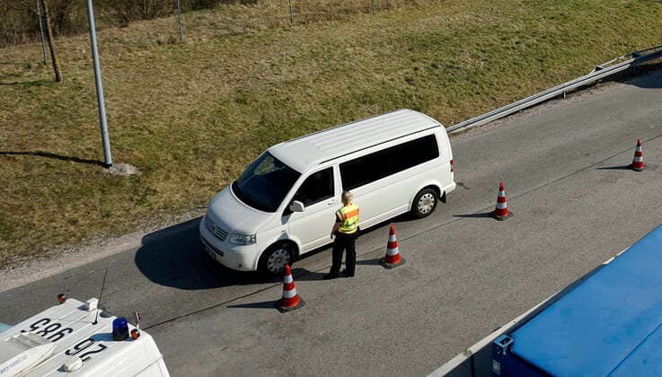 09 04 2020, Füssen in Allgäu, negative effects due to corona virus pandemic, motorway A7 direction Austria border tunnel Füssen Reutte is empty, the lane from Austria is closed in one lane, the police directs traffic to control the entry of every vehicle into the exit Police officer checks the papers of a car driver from Austria 09 04 2020, effects of tourism due to