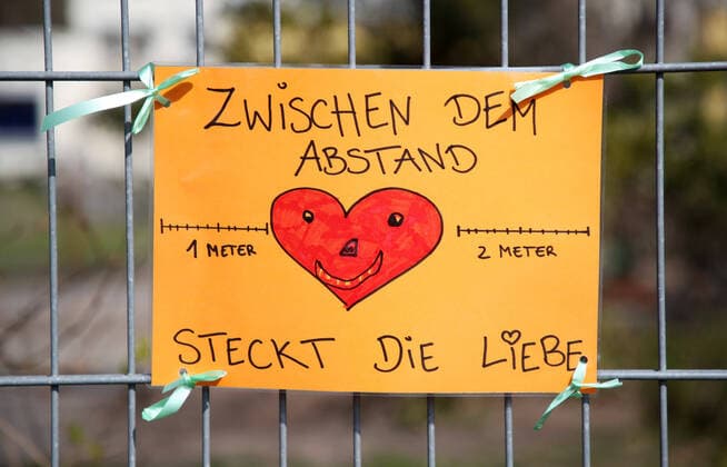 Leipzig, 09 04 2020, Precautions in the wake of the coronavirus crisis , The Fuchsbau kindergarten in Leipzig Holzhausen has opened its doors to children whose parents work in system-related professions , In the picture Shield on the fence Between the distance is love ,