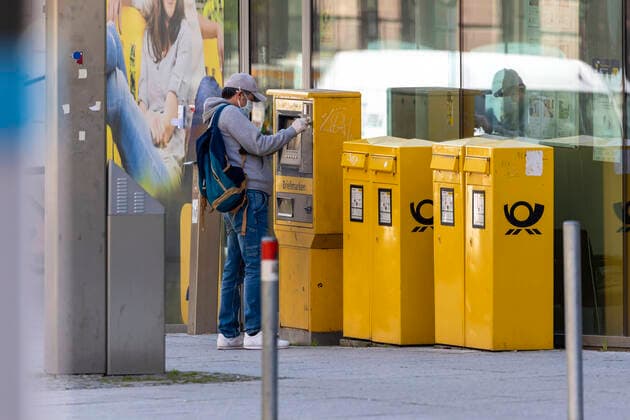 DEU, Germany, Baden Württemberg, Stuttgart, 09 04 2020 Everyday life in times of corona A man with mouth protection and protective gloves at a Deutsche Post stamp machine