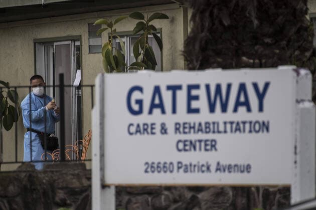 A staff member posts notices at Gateway Care & Rehabillition Center, a skilled nursing facility in Hayward, California on Thursday, April 9, 2020. Thirty-five patients have tested positive for COVID-19 along with 24 staffers. Six patients have died.  SXP2020040902 TERRYxSCHMITT