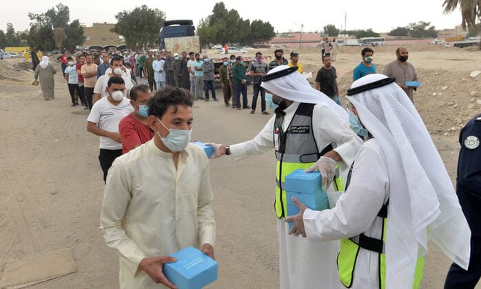 (200409) -- FARWANIYA GOVERNORATE (KUWAIT), April 9, 2020 (Xinhua) -- Workers distribute food to residents in the area of Jleeb Al-Shuyoukh in Farwaniya Governorate, Kuwait, on April 9, 2020. Kuwaiti government distributed on Thursday food baskets to residents of areas of Mahboula and Jleeb Al-Shuyoukh which are under lockdown to curb the spread of COVID-19. Kuwait reported on Thursday 55 new COVID-19 cases, bringing the total number in the country to 910, the health ministry said in a statement. (Photo by Asad Xinhua) KUWAIT-FARWANIYA GOVERNORATE-COVID-19-FOOD DISTRIBUTION 