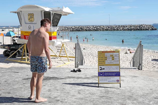 GOOD FRIDAY COVID-19, A beach goer is seen looking at a sign reminding the public about the 2 meter Social Distancing rules at Cottesloe Beach in Perth on Friday, April 10, 2020. Beaches remain open but the Western Australian government have warned the public they could be closed if people do not adhere to social distancing rules. ( NO ARCHIVING, EDITORIAL USE ONLY, NO USE IN BOOKS WITHOUT CONSENT PERTH WA AUSTRALIA  Copyright: xRICHARDxWAINWRIGHTx 20200410001462838426