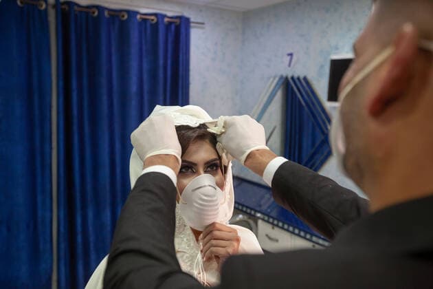 (200410) -- BETHLEHEM, April 10, 2020 (Xinhua) -- Palestinian groom, Ishaq Musleh, adjusts face mask on his bride, Shima al-Titi, before they leave the beauty salon in the Palestinian Deheisheh refugee camp near the West Bank city of Bethlehem, on April 10, 2020. Wearing masks and gloves as preventive measures, the couple celebrated their wedding during the COVID-19 outbreak. (Photo by Luay Sababa Xinhua) MIDEAST-BETHLEHEM-COVID-19-WEDDING 