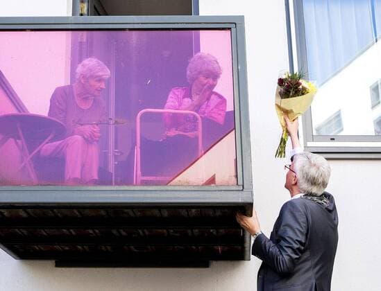 2020-04-10 14:12:41 TILBURG - Theo Weterings, burgemeester van Tilburg, deelt via een ladder bloemen uit aan ouderen in een verzorgingshuis. Op Goede Vrijdag deelt de sierteeltsector op 2200 locaties bloemen uit aan ouderen die vanwege de coronacrisis geen bezoek mogen ontvangen. ANP REMKO DE WAAL  Copyright: xANPx xREMKOxDExWAALx x409444971x
